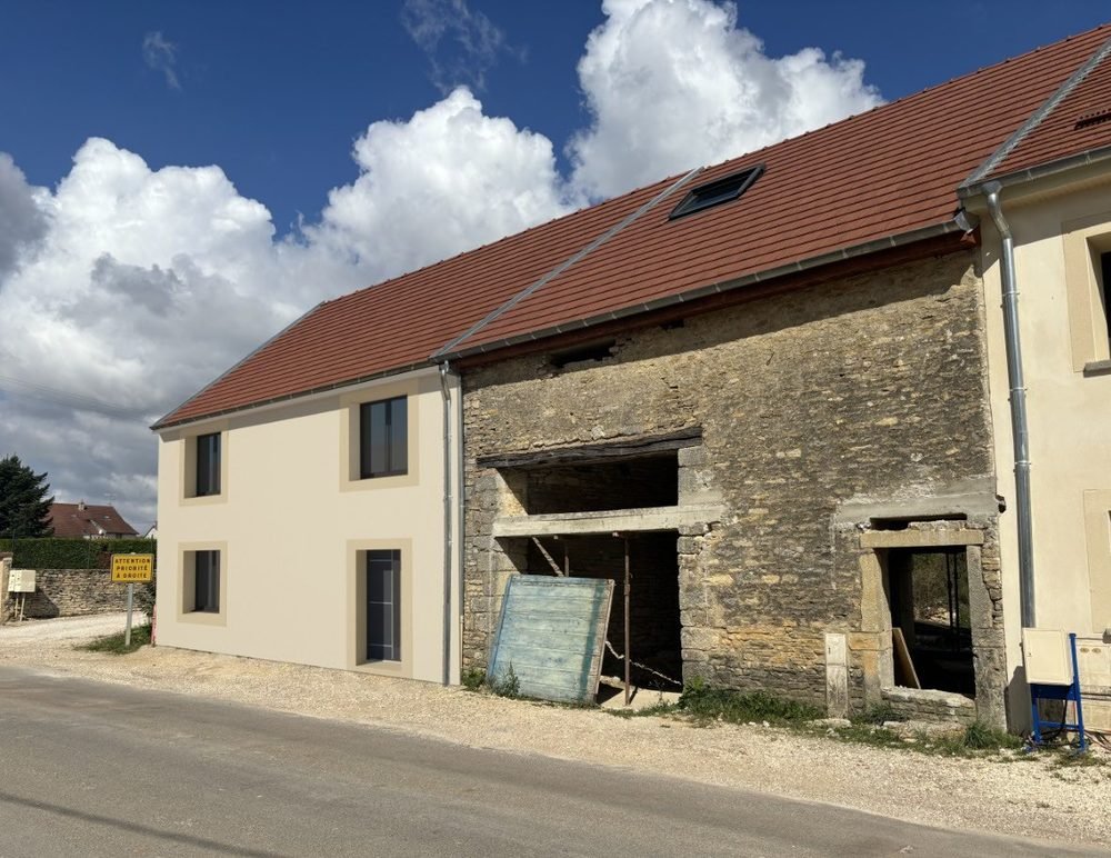 Maison neuve enduite accolée à une grange en pierre, côté rue